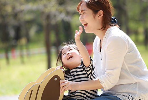 お母さんと子どもが笑顔で遊具で遊んでいる様子の写真