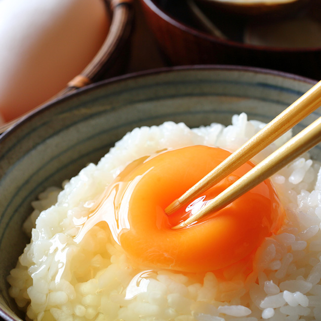 茶碗に盛られた白いご飯の上に、生卵がのっている様子