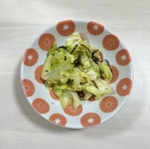 オレンジ色の模様入りの皿に盛り付けられたキャベツと塩昆布の和え物の写真