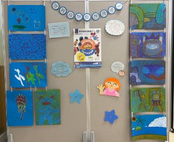 あさひなたに掲示されたブルーフラッグの写真。青い画用紙に絵や折り紙、シールなどで作られた作品。