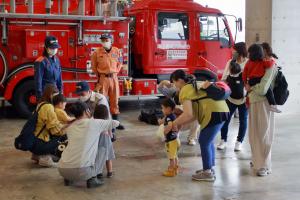 消防署見学で消防車の周りに集まる親子連れの写真