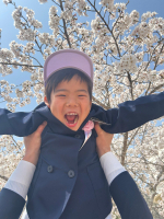 黒いコートを着てキャップを被った男の子が高い高いをしてもらって笑顔になっている写真