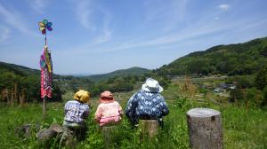 丸太の上に家族で座っているように似せている案山子の写真