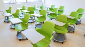 ミニテーブルが備え付けられた緑色の椅子が並べられている写真