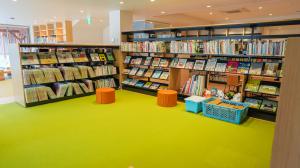 本棚に囲まれている黄緑色のマットのエリアの写真