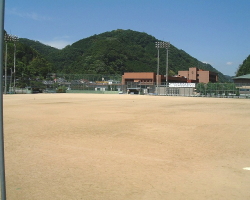 奥に山と建物があるグラウンドの写真