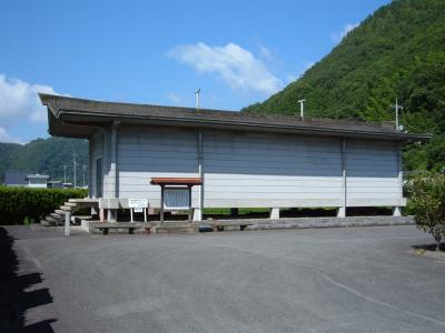 横長な建物の側に案内板が設置されている写真