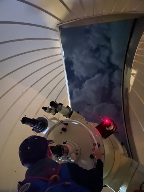 天文台の望遠鏡を覗く男の子の写真