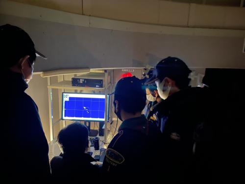 青い画面のモニターを見つめる人たちの写真