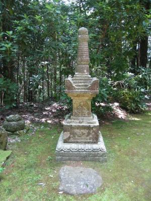 森の手前に置かれた石塔の写真