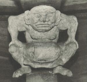 丸い顔で膝に手を置いた中腰の人の石造の写真