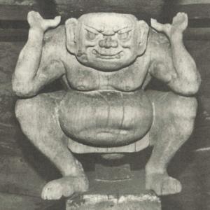 中腰で両手を頭の高さまで挙げた人の石造の写真