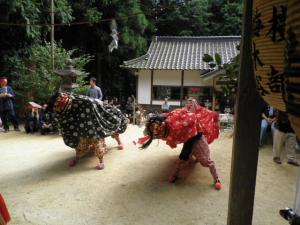 緑と赤の2匹の獅子舞が舞っている写真