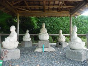 それそれ違った方向を向いて座っている5体の石造の写真