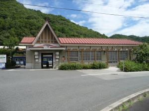 山の前に建つ赤い屋根の駅舎の写真
