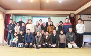 畳の部屋で記念写真にうつる地区の住民の方々の写真