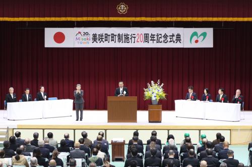 美咲町町制施行20周年記念式典と書かれた横断幕のあるステージの上で男性が壇上にあがっている写真