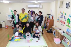 風船で作ったおもちゃを持ちながら記念撮影に臨む親子連れの写真
