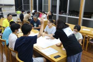 民話館の一室でテーブルを囲んで意見交換をする高校生たちの写真