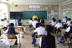 中学校の教室で担当者の話に耳を傾けている中学生たちの写真