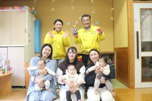 保育園の一室で赤ちゃんを抱きながら記念撮影に臨むお母さんたちの写真