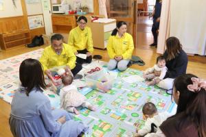 ケースの中に入っているおもちゃを赤ちゃんに見せているスタッフの方々の写真