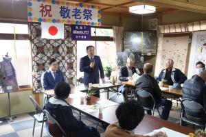 意見交換会の議場でマイクを持って発言をしている男性に耳を傾ける老人クラブの方々の写真