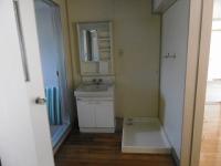 中央に鏡付き洗面化粧台が備え付けられ、左に青いシャワーカーテンがある脱衣所の写真