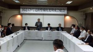 白布を被せロの字型に配置された長机に着席し会議を行う人々の写真