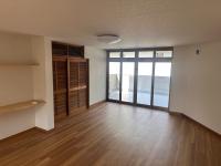 手前にフローリングの空間、奥に全面ガラス張りの引き戸とテラスが見えるリビングの写真